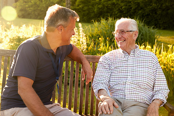 Two men sitting on a park bench chatting