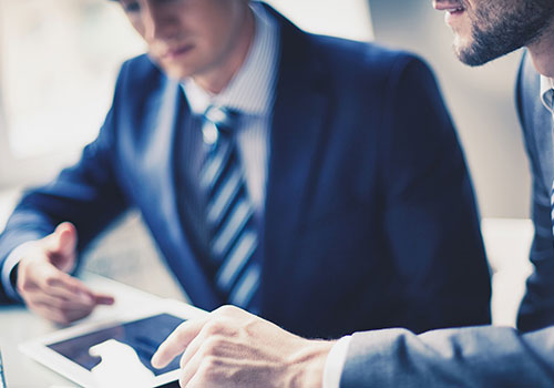 Business men discussing finance details on tablet computer screen